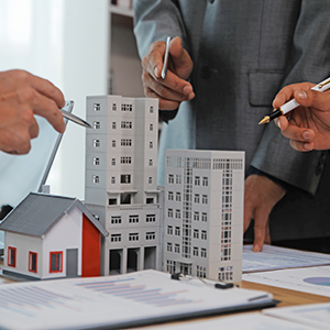 People reviewing property documents with building models and a house model on a table
